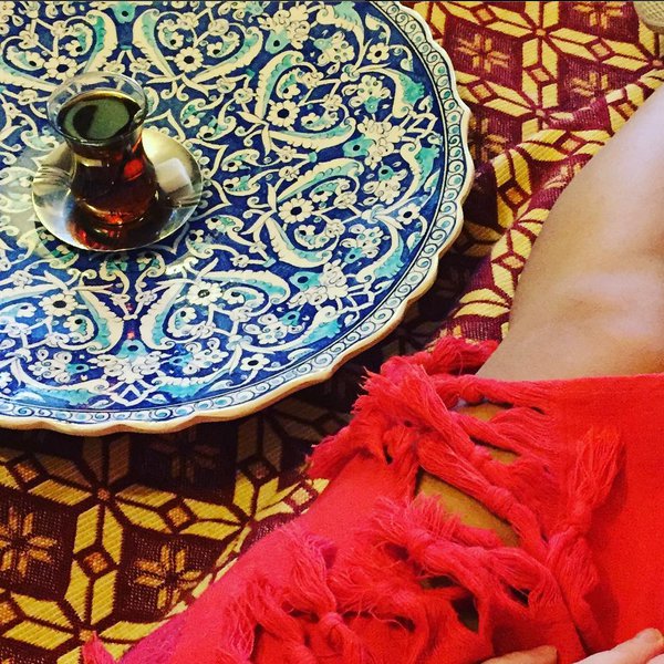 Frauenbein in Decke neben einem Glas türkischen Tees